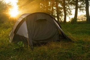 turist tält på flodbank på soluppgång foto