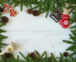 jul gräns med gran träd grenar, jul dekorationer och godis sockerrör på vit trä- styrelser foto