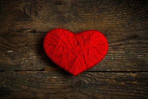 röd hjärta form tillverkad från ull på gammal sjaskig trä- bakgrund foto