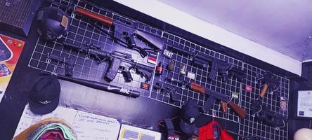 en samling av svart långpipig vapen repliker är visas på en vägg hylla. guns m4, ak47 och andra foto