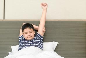 fet fett pojke vaknar upp och stretching på säng i morgon, Bra morgon- värld begrepp foto