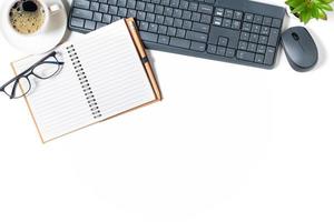vit kontor skrivbord tabell, tom anteckningsbok med bärbar dator och svart kaffe isolerat foto