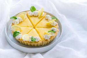 citron- syrlig citrus- kaka i vit maträtt och vit trasa bakgrund, foto