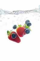 jordgubb och blåbär stänk in i vatten, sommar dryck foto