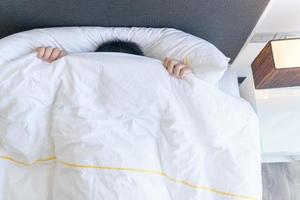 lat pojke beläggning hans ansikte med filt medan liggande i säng på Hem, foto
