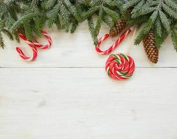 jul gräns med gran träd grenar med koner och godis sockerrör på vit trä- styrelser redo foto