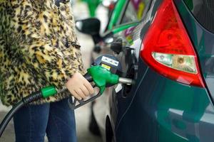 kvinna fyllningar bensin in i henne bil på en gas station i vinter- foto