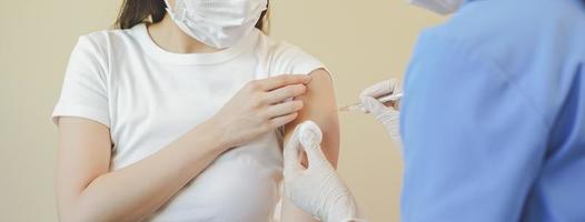 covid-19, coronavirus hand av ung kvinna sjuksköterska, läkare ger spruta vaccin, injicera skott till asiatisk vapen patient. vaccination, immunisering eller sjukdom förebyggande mot influensa eller virus pandemi begrepp. foto