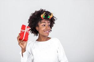 upphetsad svart kvinna skakning insvept gåva låda tar emot presenterar på henne födelsedag eller jul stående över vit bakgrund. studio skott foto