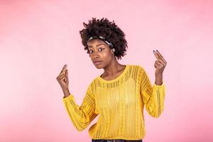 självsäker ung svart kvinna Framställ i gul vinter- Tröja över rosa studio bakgrund foto