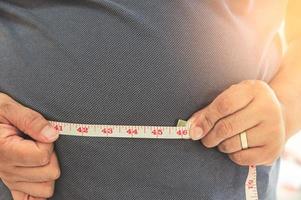 fett mogna man mätning hans mage med mått tejp. fetma och vikt förlust begrepp foto