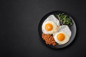 utsökt hjärtlig frukost bestående av två friterad ägg, konserverad linser och mikrogrönsaker foto