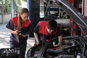 två professionell bil- mekanisk partners kolla upp och reparera ett ev bil batteri och hybrid motor på en underhåll garage, expert- elektrisk fordon service, och fixering yrken bil industri. foto