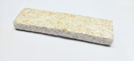 tempe mentah. rå tempeh, okokt sojaböna kaka från indonesien i en plast på vit bakgrund foto