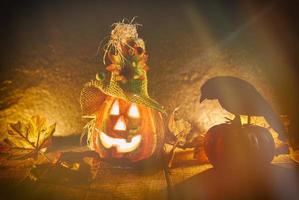 halloween pumpa scarecrow lykta med torr sugrör på trä- - huvud domkraft o lykta ondska ansikten läskigt Semester dekorera på halloween bakgrund och kråka Sammanträde på pumpa foto