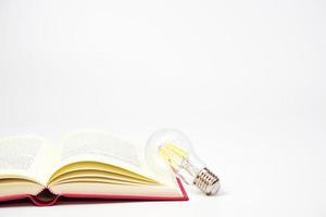 ljus Glödlampa lysande med bok på vit bakgrund. begrepp av kunskap, visdom, ny idéer och kreativitet. foto
