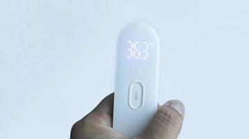en hand innehav digital termometer som visar vanligt temperatur med isolerat på vit. foto