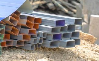 grupp av fyrkant stål rektangel rör metall järn produktion profiler rör på de jord. fyrkant metall rör för bakgrund använder sig av metall rör och stavar, stål material, byggnad material. foto