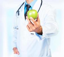 läkares hand innehav en färsk grön äpple närbild foto