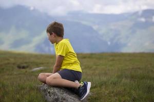 en liten pojke utseende på de berg, beundrar natur. foto