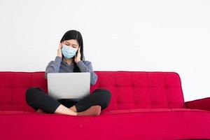 trött kvinna som bär en ansiktsmask, huvudvärk och migrän, lidande av kontorssyndrom efter långa timmars arbete på datorn. kontorssyndrom och hälsovårdskoncept. foto