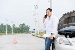 asiatisk män förare kolla upp för skada efter en bil olycka innan tar bilder och sändning försäkring. uppkopplad bil olycka försäkring krav efter lämna in foton och bevis till ett försäkring företag.