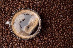 de topp se av en kaffe kopp och grupp av svart kaffe bönor är de bakgrund. stark svart espresso, grunder av kaffe bakgrund, textur foto