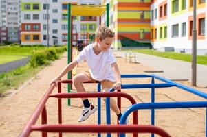 en Tonårs pojke är engagerad på horisontell barer nära de skola foto