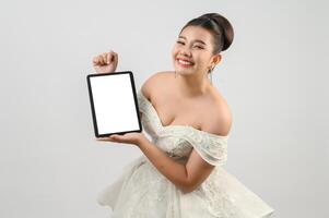 ung asiatisk skön brud utgör med attrapp läsplatta i hand foto