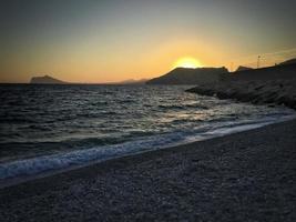 medelhavsstrand utan människor vid solnedgången i calpe, alicante foto