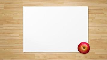 rött äpple på vitbok på träbakgrund foto