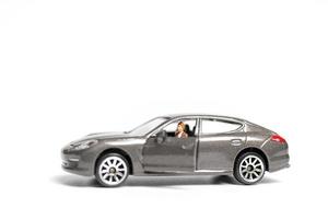 miniatyrfolk som sitter på en bil på en vit bakgrund foto