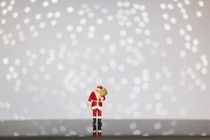 miniatyr jultomten bär en påse på en bokeh bakgrund, god jul och gott nytt år koncept. foto