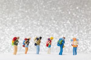miniatyrbackpackers som går på en snöbakgrund, vinterkoncept foto