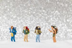 miniatyrbackpackers som går på en snöbakgrund, vinterkoncept foto