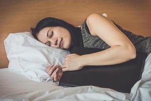 kvinna som sover på sängen, med bärbar dator foto