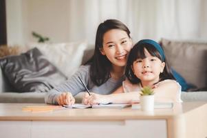 lycklig asiatisk familjemor och dotter som studerar tillsammans foto