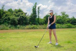 porträtt av golfspelare asiatisk kvinna innehav golf trä på de Land klubb, glad kvinna koncept, sätta golf på stift foto