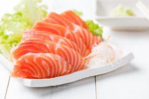 lax sashimi på vit maträtt och trä bakgrund foto