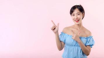 porträtt ung skön asiatisk kvinna Lycklig leende pekande finger och hand till som visar på kopia Plats isolerat på rosa bakgrund. attraktiv kvinna person gest uppmärksamhet till detta befordran. foto
