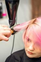 frisör torkar rosa hår av kvinna foto