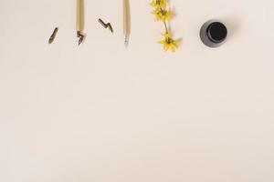 kalligrafi, skarp penna, bläck, fjädrar, forsythia blomma på beige bakgrund med kopiering Plats foto