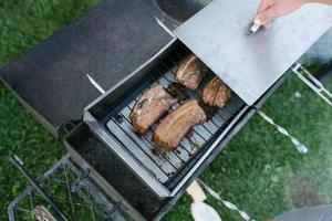 bacon är rökt i en metall rökeri i de öppen luft foto