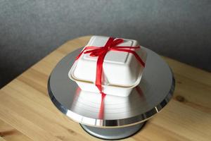 vit låda med röd band för kaka bento på bakverk metall skivspelare för kakor foto