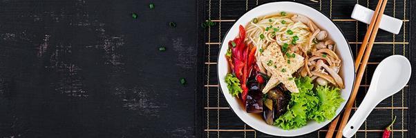 asiatisk vegan spaghetti soppa med tofu ost, shimeji svamp och friterad äggplanta i skål på mörk bakgrund. baner. topp se foto