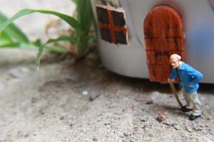 miniatyr- figur av en farfar vem är väntar i främre av de hus. foto