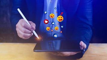 social media och uppkopplad digital begrepp, affärsman använder sig av bärbar dator sändning emojis med social media. foto