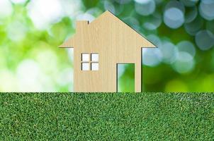 hus ikon från trä- på gräs textur natur bakgrund som symbol av inteckning, dröm hus på natur bakgrund och Plats för din text foto