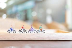 miniatyrfolk som cyklar på en träbro, hälsovårdskoncept foto