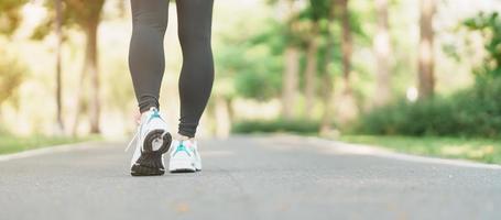 kvinna joggning och gående på de väg på morgon, ung vuxen kvinna i sport skor löpning i de parkera utanför, ben muskler av idrottare. träning, friskvård, friska livsstil och träna begrepp foto